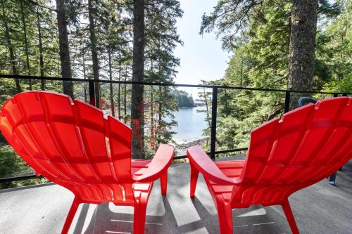 two red chairs sitting on a porch with a view of a lake at The Cabins at Terrace Beach in Ucluelet