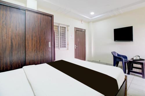 a bedroom with a bed and a tv and a desk at Super Hotel O Ramavarapadu Near PVR Icon in Vijayawada