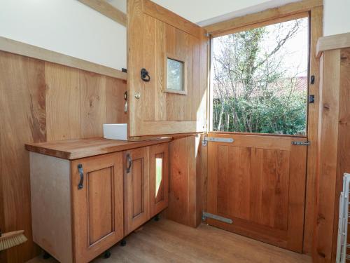 una cocina con armarios de madera y una gran ventana en Ty Golchi, en Bangor