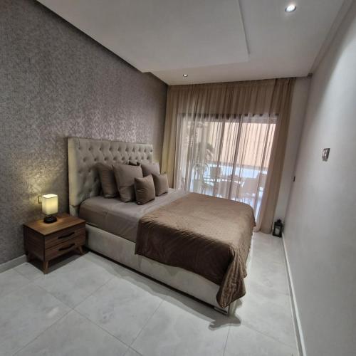 a bedroom with a large bed and a window at mehdia apartment and terrace parking fiber netfli in Kenitra