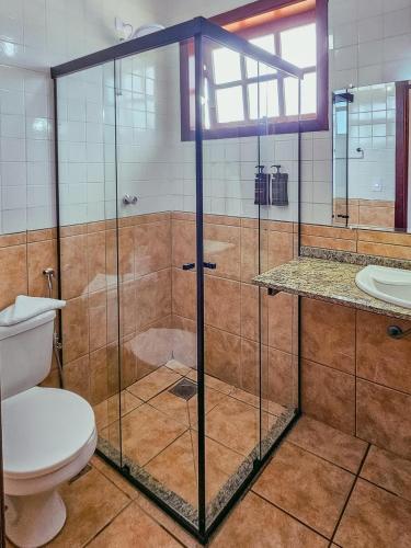 a bathroom with a glass shower with a toilet at Pousada Ubatuba Villa Tupi in Ubatuba