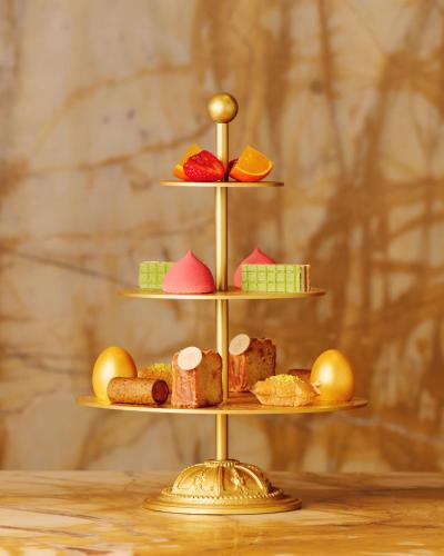 a three tiered display of pastries on a gold stand at Hotel Cafe Royal in London
