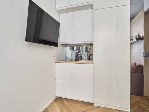 une cuisine avec des armoires blanches et une télévision à écran plat dans l'établissement Superb studio Tour Eiffel Champ de Mars, à Paris
