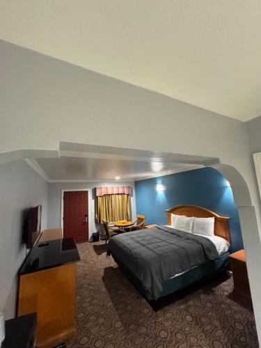 a bedroom with a bed and a desk and a tv at Sunset Inn & Suites in Gardena