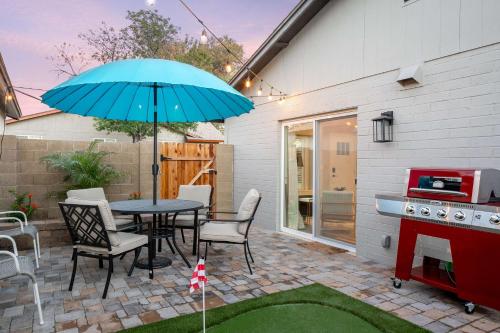 a patio with a table with a blue umbrella at Casa Evergreen - Outdoor Grille Patio with Putt in Leisure World
