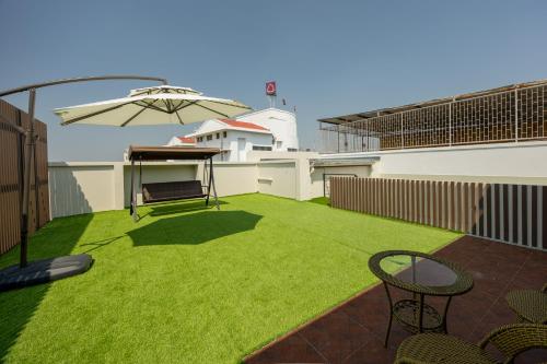 a patio with grass and an umbrella and chairs at Diff Apartel Banglamphu in Bangkok