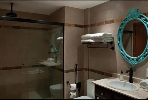 Un baño con ducha, lavabo y espejo. en BUONA VITTA Gramado Apto 413, en Gramado