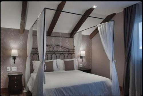 1 dormitorio con 1 cama blanca grande con dosel en BUONA VITTA Gramado Apto 413, en Gramado