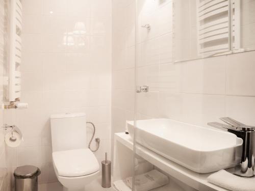 a white bathroom with a toilet and a sink at Hotel Betmanowska Main Square Residence Adults Only in Kraków