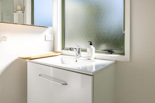 une salle de bain avec un lavabo et un miroir dans l'établissement Tranquility Cottage, Oneroa - Be My Guest Waiheke, à Waiheke Island