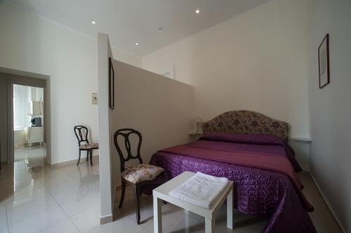 a bedroom with a bed and two chairs and a table at Flora Rooms in Campobasso