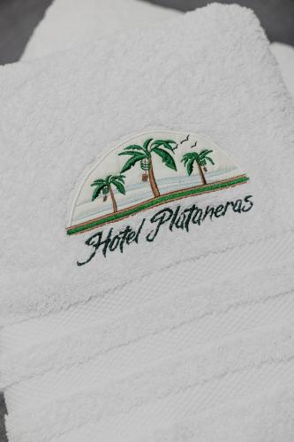 a white towel with palm trees on it at Hotel Plataneras Caney in Turbo