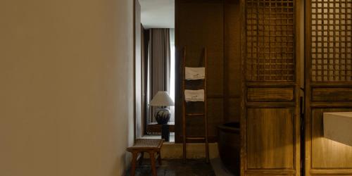 a room with a chair and a table and a lamp at Huangshan Yixian Pumanmanju Hotel in Huangshan