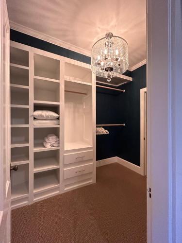 a walk in closet with a chandelier and white cabinets at 210 Main St in Ellsworth