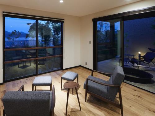 a living room with chairs and a large window at 宮島離れの宿 IBUKU -Miyajima Hanare no Yado IBUKU- in Miyajima