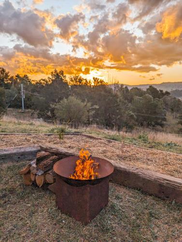 a fire pit in a field with the sunset in the background at Kanimbla Sunsets by Tiny Away in Kanimbla