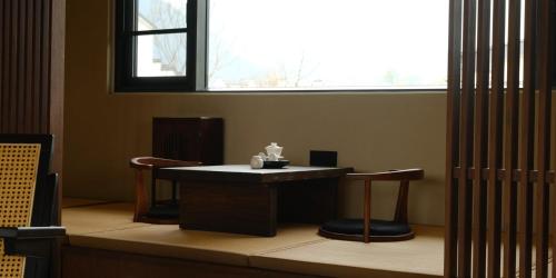 a table and two chairs in a room with a window at Huangshan Yixian Pumanmanju Hotel in Huangshan