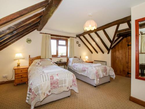 two beds in a bedroom with wooden ceilings at White Cottage in Hopton Wafers
