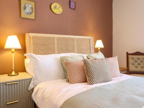 a bedroom with a white bed with pillows at Derwen House in Llangollen