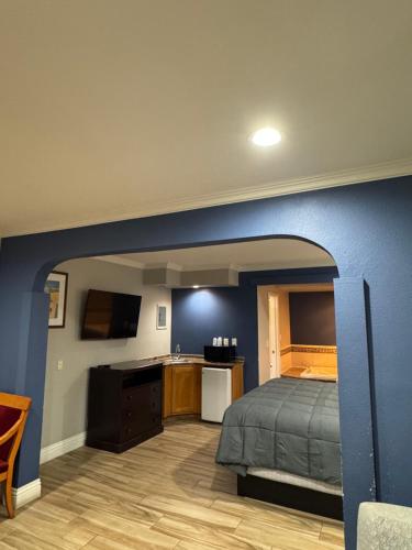 a bedroom with a bed and a blue wall at Sunset Inn & Suites in Gardena