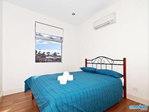 a bedroom with a bed with a blue comforter at The Block Escape - Ocean Views No 6 in Victor Harbor