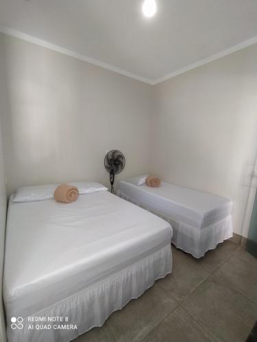 due letti in una stanza con pareti bianche di Casa Pirenópolis a Pirenópolis
