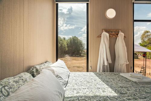 a bedroom with a bed and a window with a wedding dress at Fassifern Tiny House 1 by Tiny Away in Lancefield