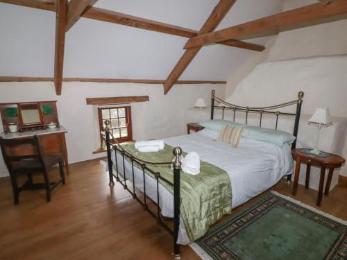a bedroom with a bed and a desk and a chair at Panteurig Cottage in Goodwick