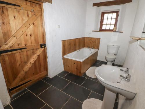 a bathroom with a wooden door and a tub and a toilet at Panteurig Cottage in Goodwick