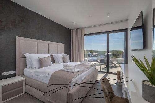 a bedroom with a large bed and a balcony at Villa One Debeljak Zadar in Debeljak