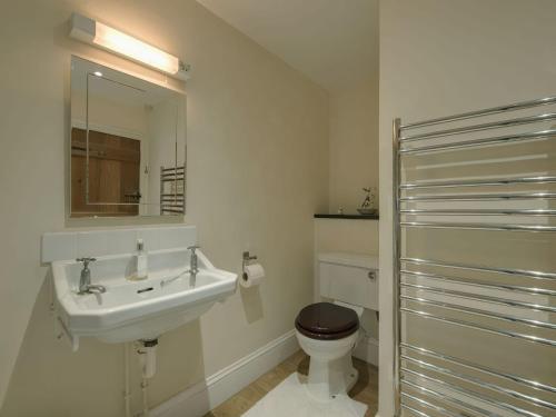a bathroom with a sink and a toilet and a mirror at The Farmhouse in Tavistock