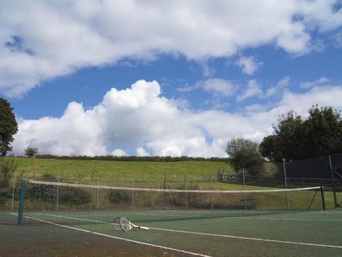 a tennis net on a tennis court with a field at The Farmhouse in Tavistock