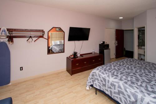 a bedroom with a bed and a dresser and a mirror at Scottish Inns & Suites - North Hershey in Harrisburg
