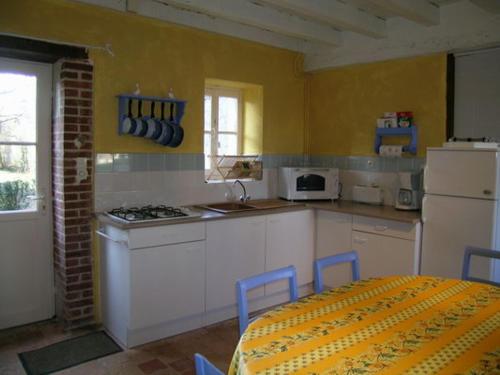 une cuisine avec une table et des chaises et une cuisine aux murs jaunes dans l'établissement Charmant gîte au château rénové, parc privé, 2 chambres, proche Nevers et circuit Magny Court - FR-1-489-163, à Le Veurdre