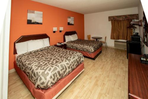 two beds in a room with orange walls and wooden floors at Scottish Inns & Suites - North Hershey in Harrisburg