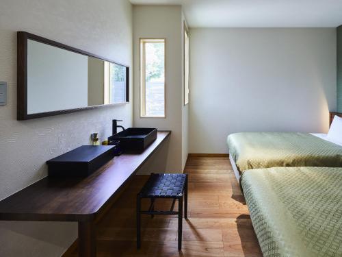 a bathroom with a vanity with a sink and a bed at 宮島離れの宿 IBUKU -Miyajima Hanare no Yado IBUKU- in Miyajima