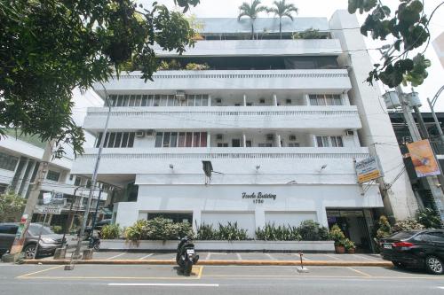 a motorcycle parked in front of a white building at Stay Malate Hostel by RedDoorz in Manila