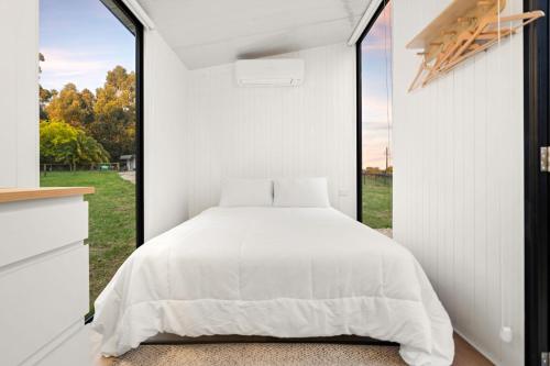 a bedroom with a bed and a large window at Glorious Escape by Tiny Away in Jindivick