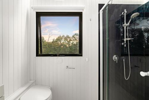 a bathroom with a window and a toilet and a shower at Glorious Escape by Tiny Away in Jindivick