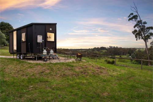 a black tiny house on a trailer in a field at Glorious Escape by Tiny Away in Jindivick