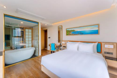 a bedroom with a large bed and a bath tub at Sala Quy Nhon Beach Hotel in Quy Nhon