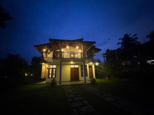 a house with a balcony at night at SaDev Lake Villa Bandaragama in Bandaragama