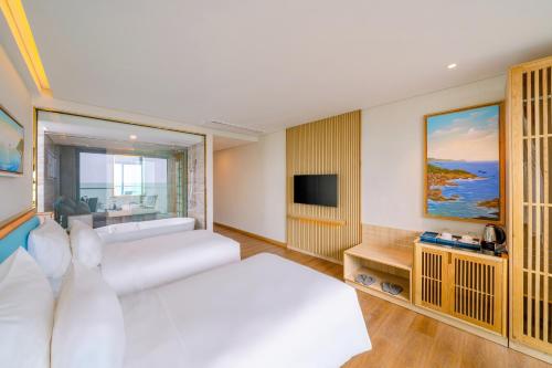 a living room with a white couch and a television at Sala Quy Nhon Beach Hotel in Quy Nhon
