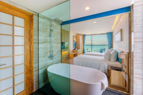 a bathroom with a bed and a tub in a room at Sala Quy Nhon Beach Hotel in Quy Nhon