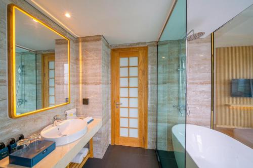 a bathroom with a sink and a tub and a mirror at Sala Quy Nhon Beach Hotel in Quy Nhon