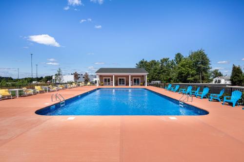 a swimming pool with blue chairs and a building at Stone Park Ellsworth-Bar Harbor in Ellsworth