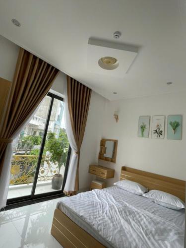 ダナンにあるLAKSHMI APARTMENT & HOTElのベッドと大きな窓のある寝室
