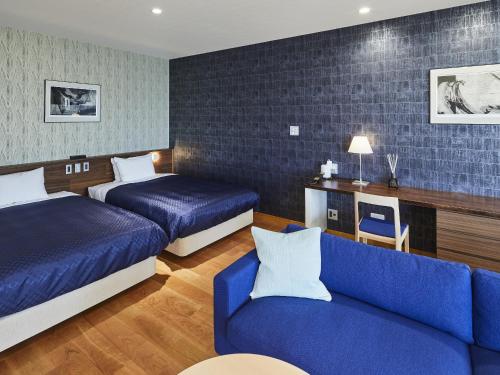 a hotel room with two beds and a blue couch at 宮島離れの宿 IBUKU -Miyajima Hanare no Yado IBUKU- in Miyajima