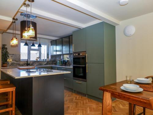 a kitchen with green cabinets and a wooden table at Hyrst Rise in Forest Row