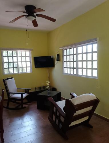 a living room with two chairs and a ceiling fan at Apartment in Finca Mayfran in Xul-Ha